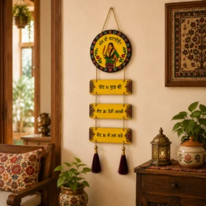Yellow Punjabi wall hanging with traditional artwork and maroon tassels decorating a living room